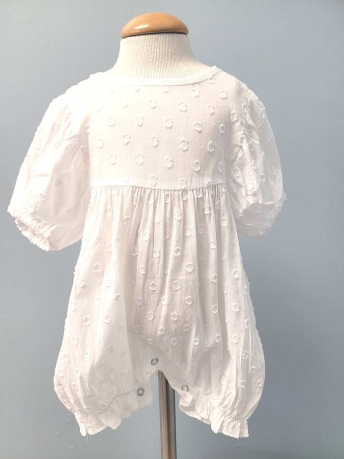 White baby romper with dot pattern.
