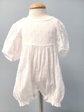 White baby romper with dot pattern.