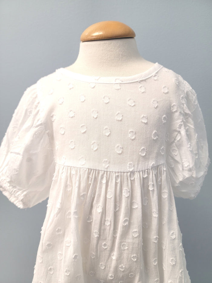 White baby romper with dot pattern.
