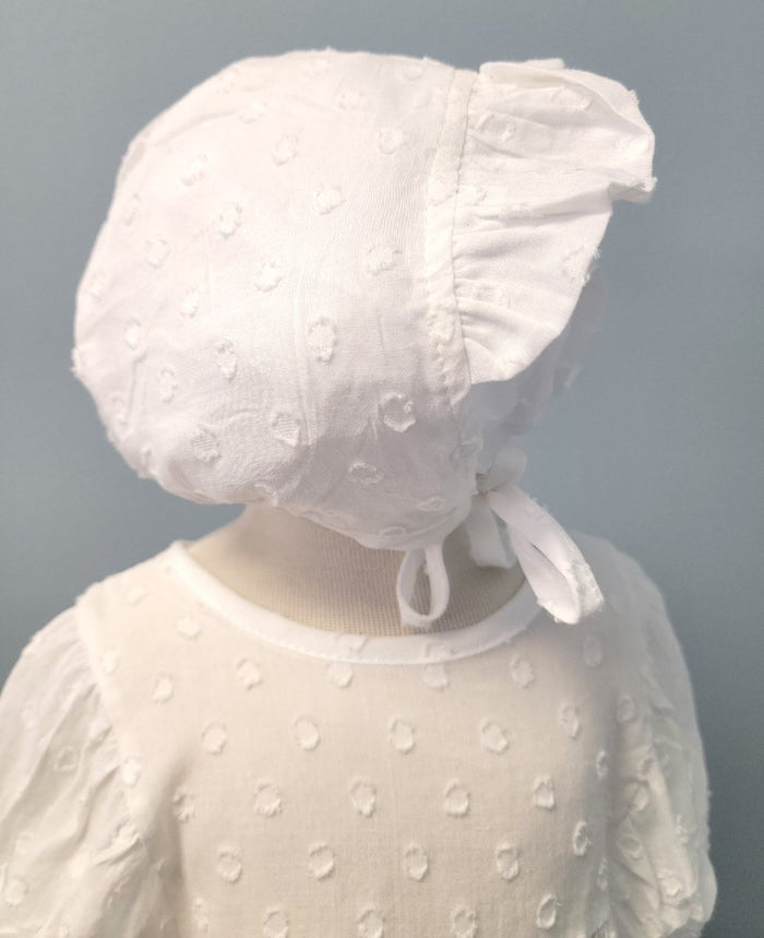 White baby romper with dot pattern and matching bonnet.