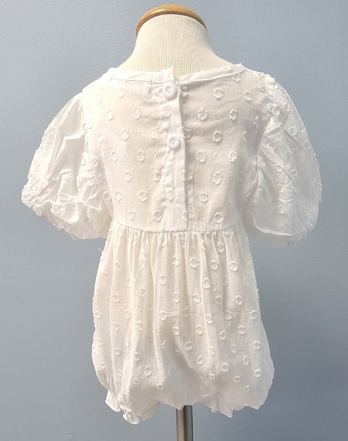 Back of white dotted baby romper with button closure.
