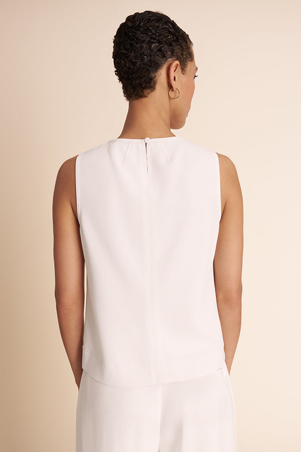 Woman wearing a white sleeveless dress against a beige background | Exclude