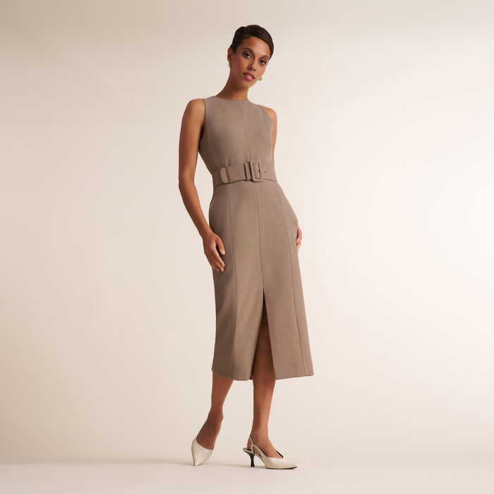 A model wears a sleeveless taupe midi dress with a matching belt and double buckle detail at the waist, paired with white pointed-toe heels, against a solid light beige studio background. | Lead