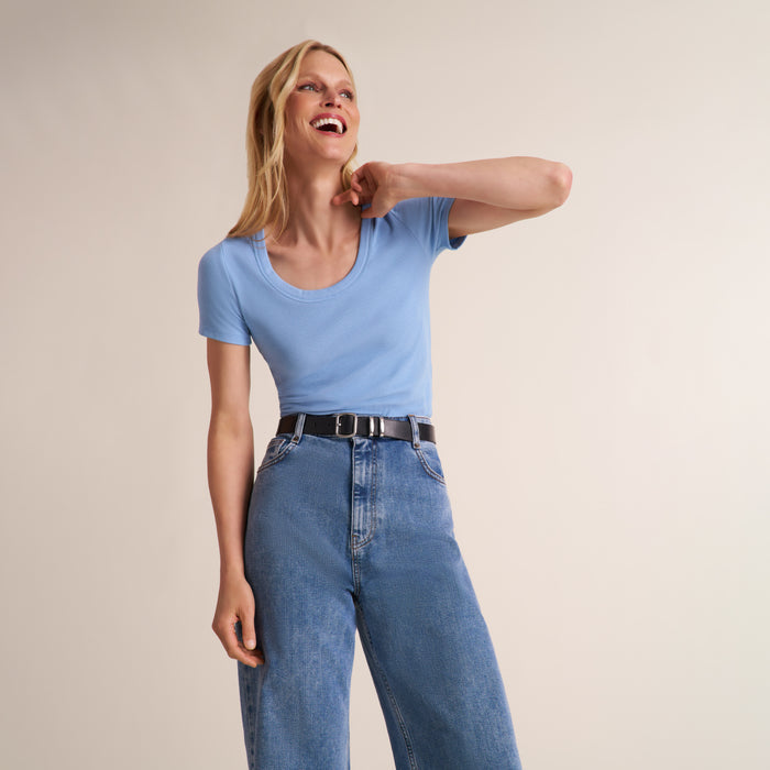 Woman wearing a light blue scoop neck short sleeve t-shirt with jeans and a belt | Lead