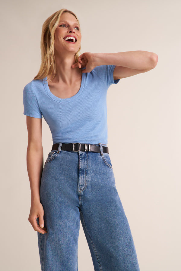 Woman wearing a light blue scoop neck short sleeve t-shirt with jeans and a belt | Exclude | Grid