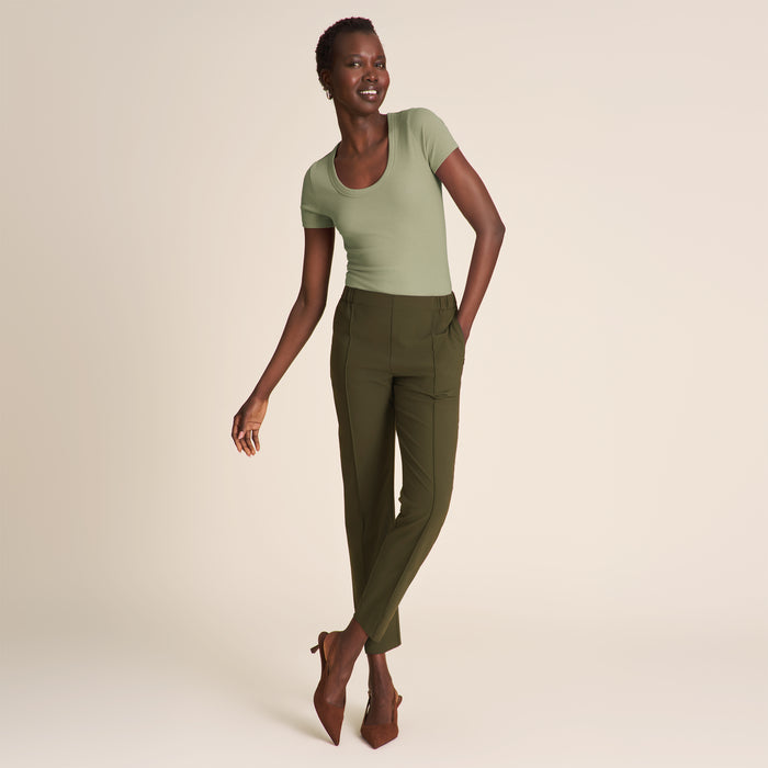 Woman wearing a green top and olive pants on a beige background | Lead