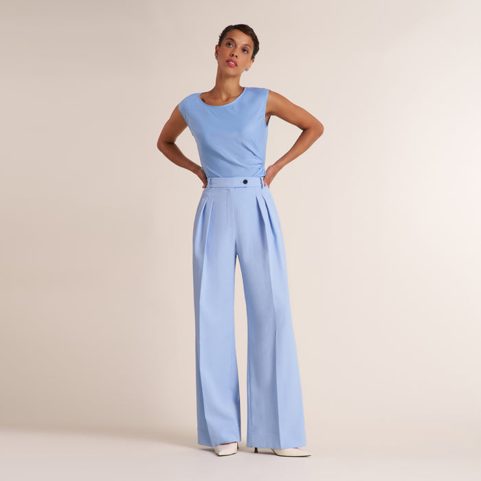 Woman wearing a light blue pant and top on a beige background