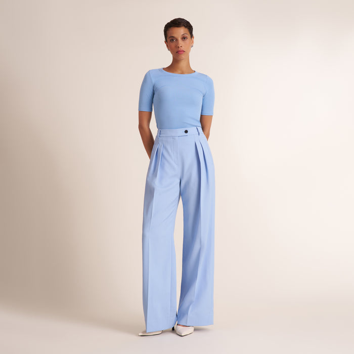Woman wearing a light blue pant and top on a beige background