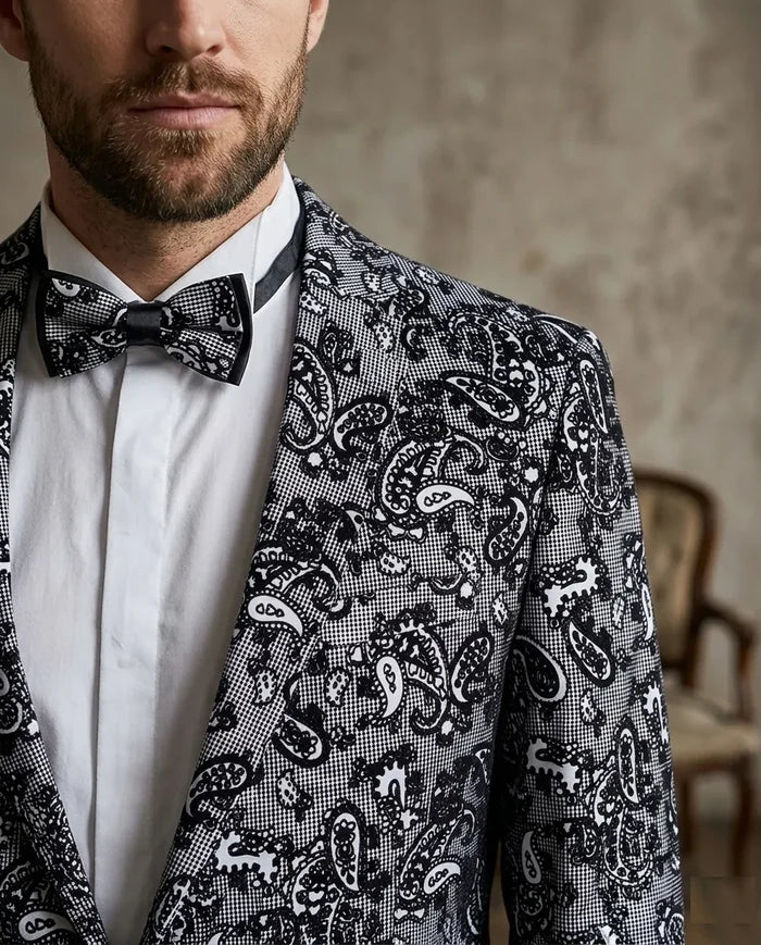Man wearing a patterned suit jacket with a bow tie against a neutral background