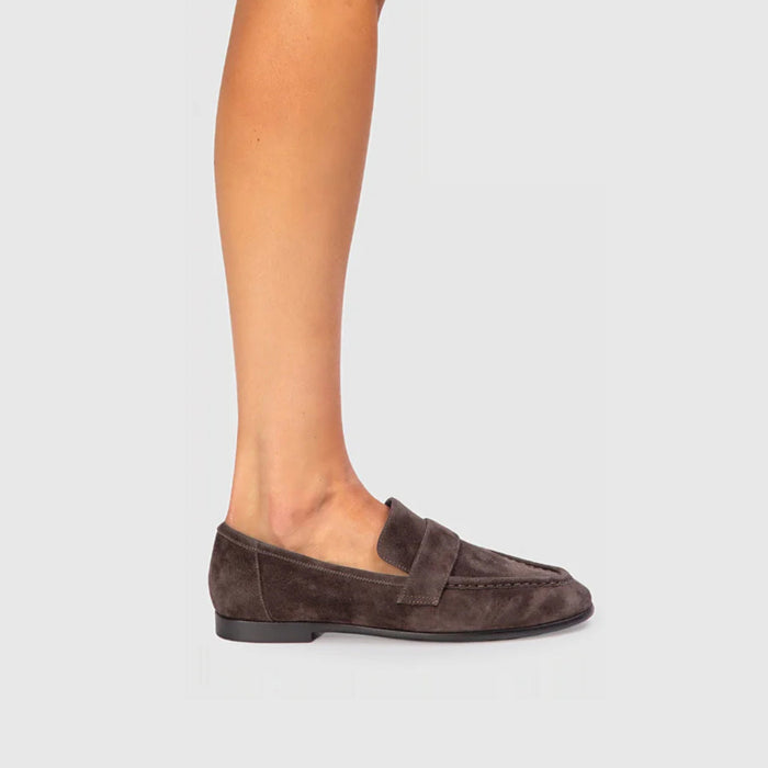 Brown loafers worn by a person on a light gray background