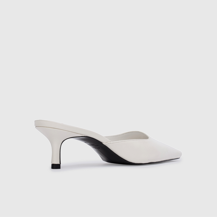 White high-heeled shoes with black accents on a light gray background