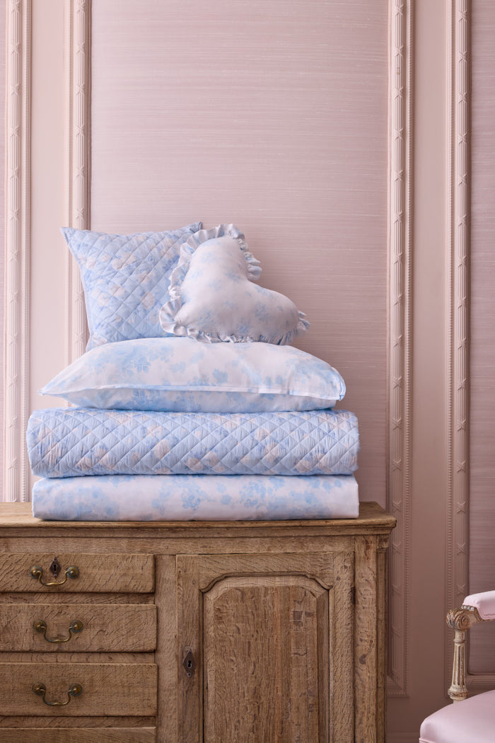 Blue and white ruffled floral plush bedding stacked and folded