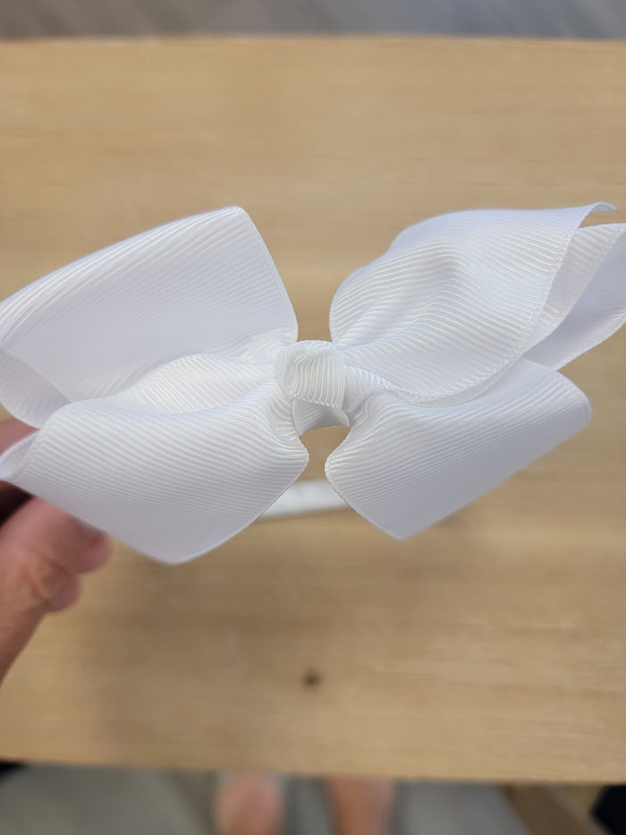White ribbon bow on thin white headband.