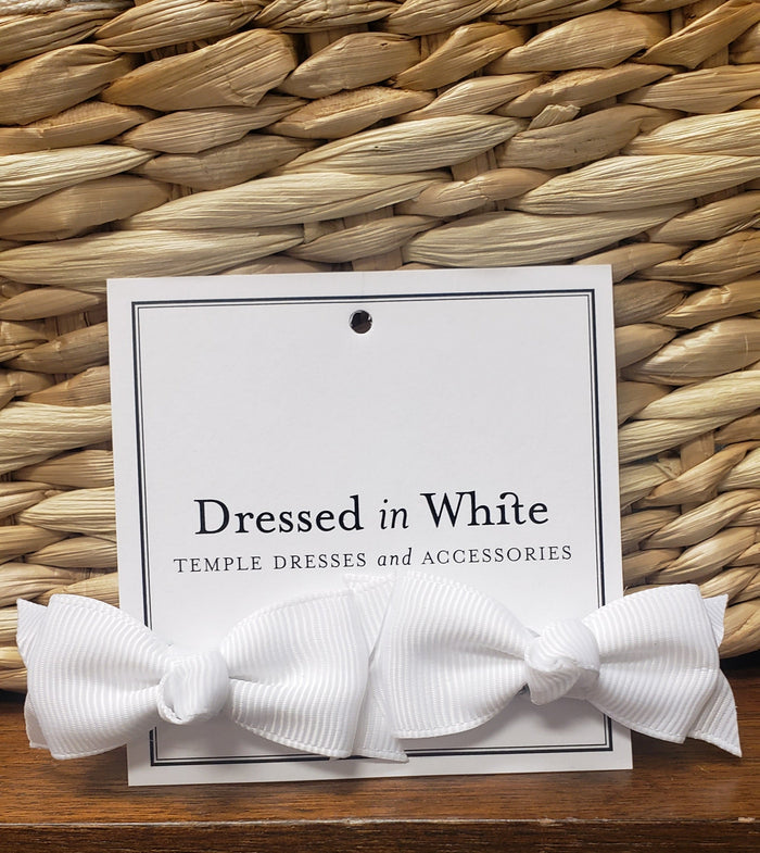 Two small white bow hair clips.