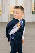 boy in navy suit with coat over shoulder