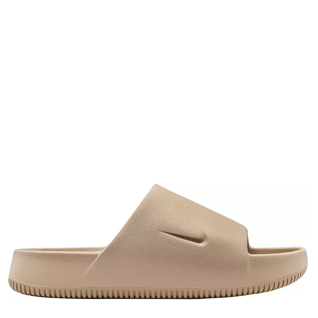 A pair of beige Nike slides with a contoured design and textured footbed.