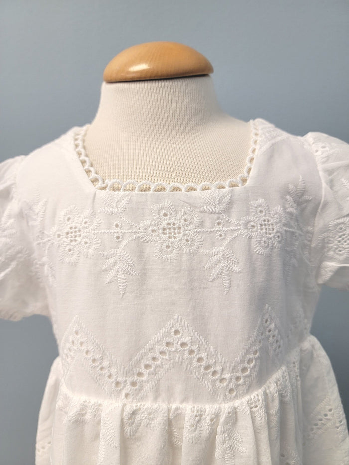 White baby dress with a square neck.