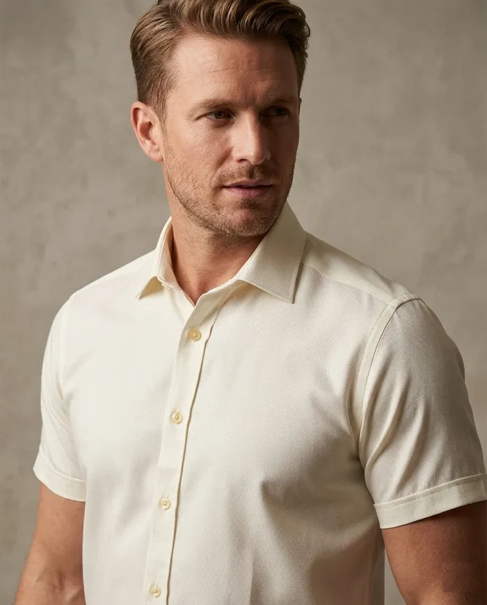 Man wearing a white short-sleeve shirt against a neutral background