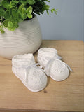 White baby booties with ribbon bow.
