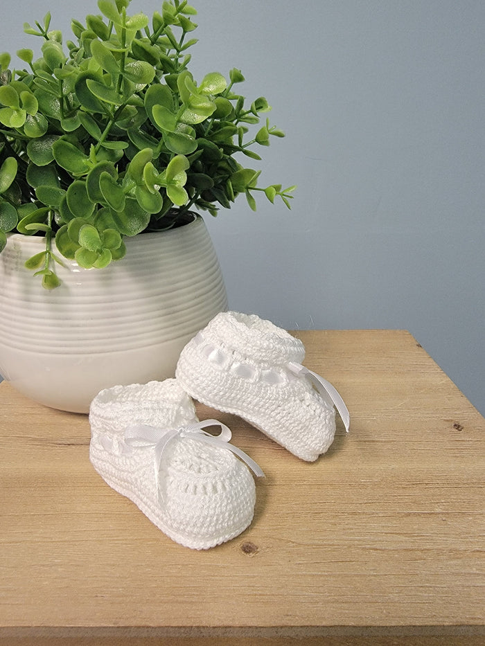 White baby booties with ribbon bow.