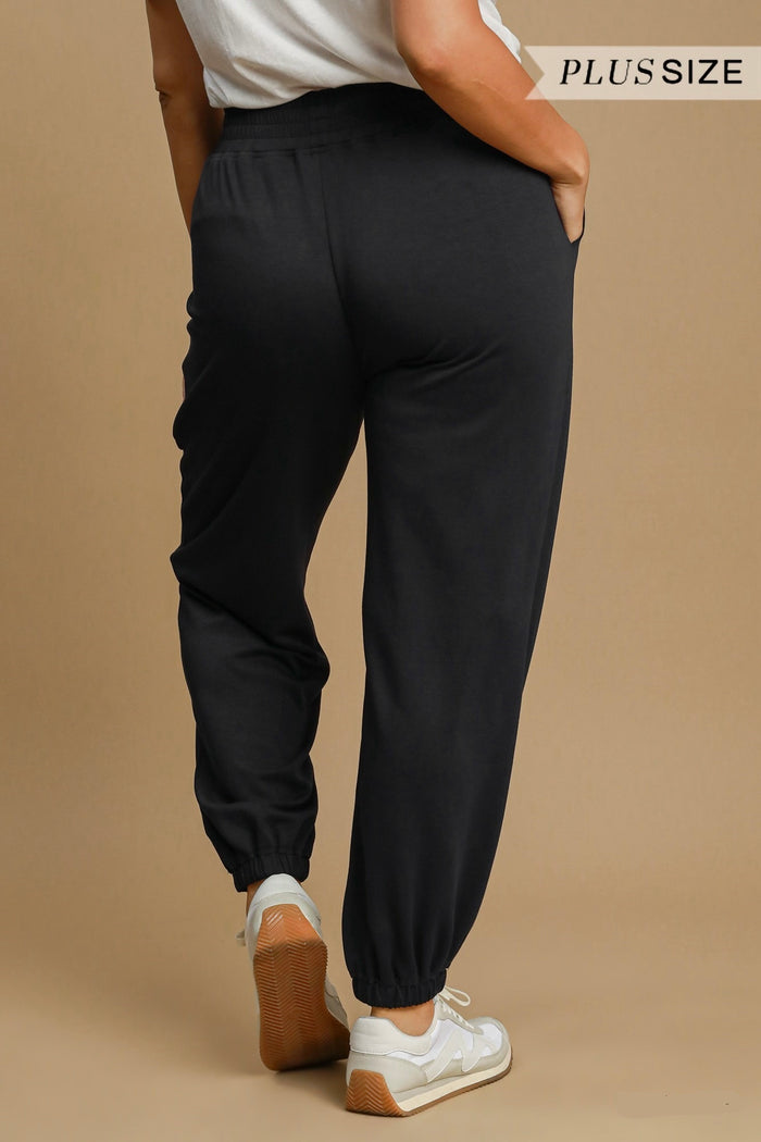 Women's black scuba luxe knit jogger pants with raw/reverse seam details by Umgee in plus size showing back view