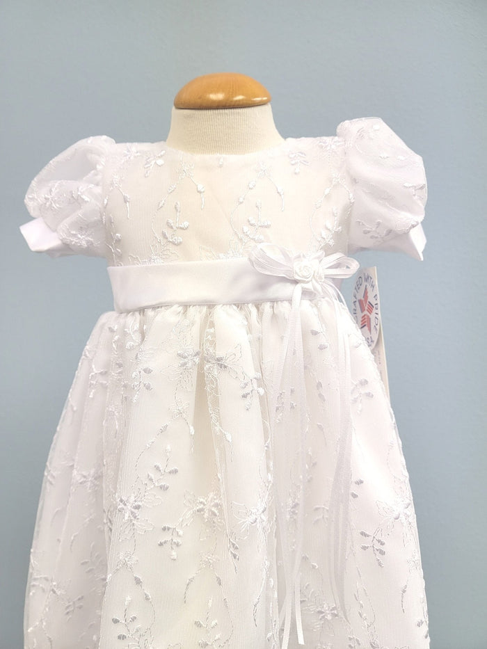 White baby gown with floral embroidery and rosette bow.