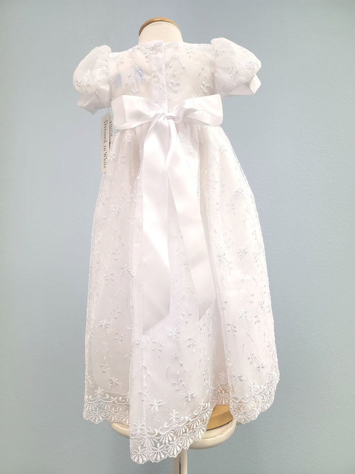 Back of white embroidered baby gown with buttons and tie bow.