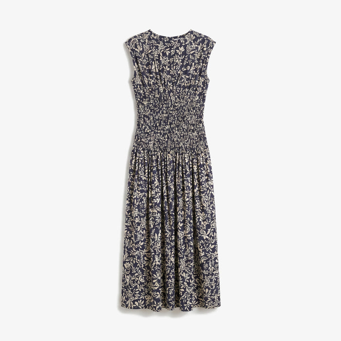 A sleeveless midi dress with a smocked bodice and an all-over abstract floral print in navy blue and cream, shown against a plain light gray background.