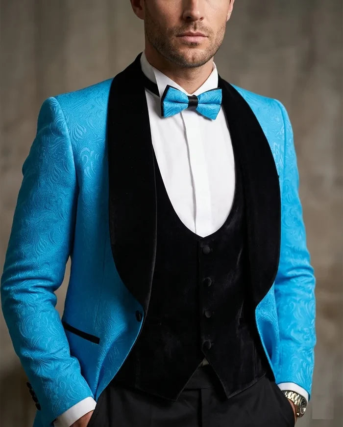 Man wearing a blue suit jacket with a black vest and bow tie against a neutral background