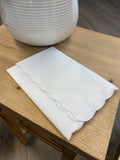 Folded white hankie with scalloped edge.
