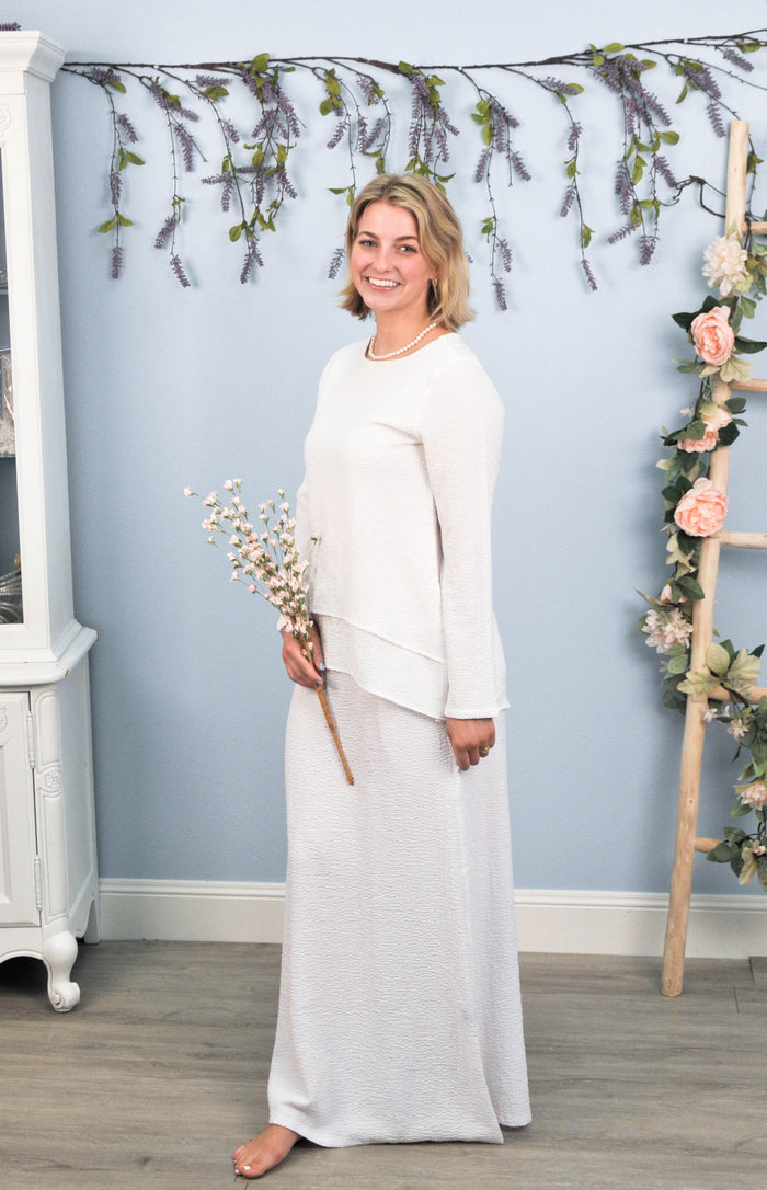 woman in white skirt and blouse holding flowers