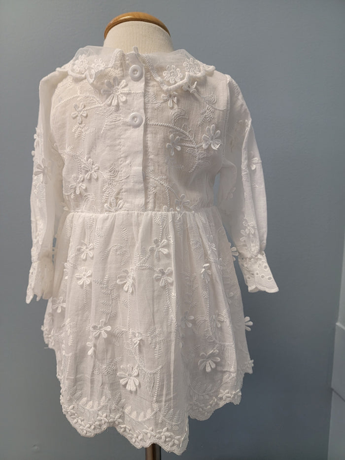 Back of white baby dress with button closure.