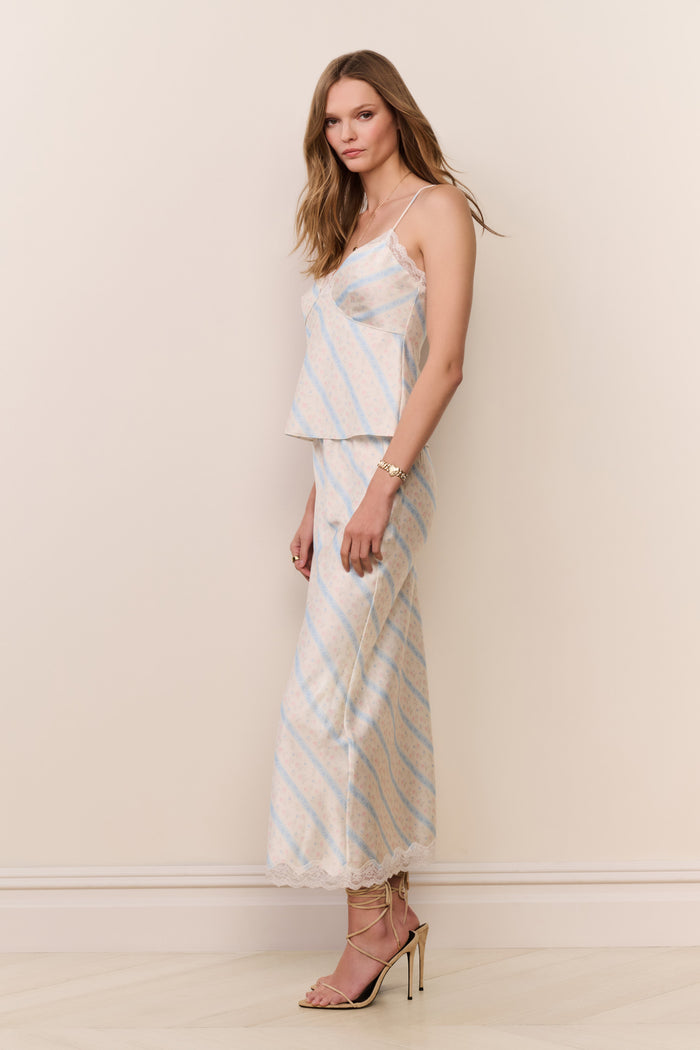 Woman wearing a Beige skirt with light blue stripes and matching top against a plain background