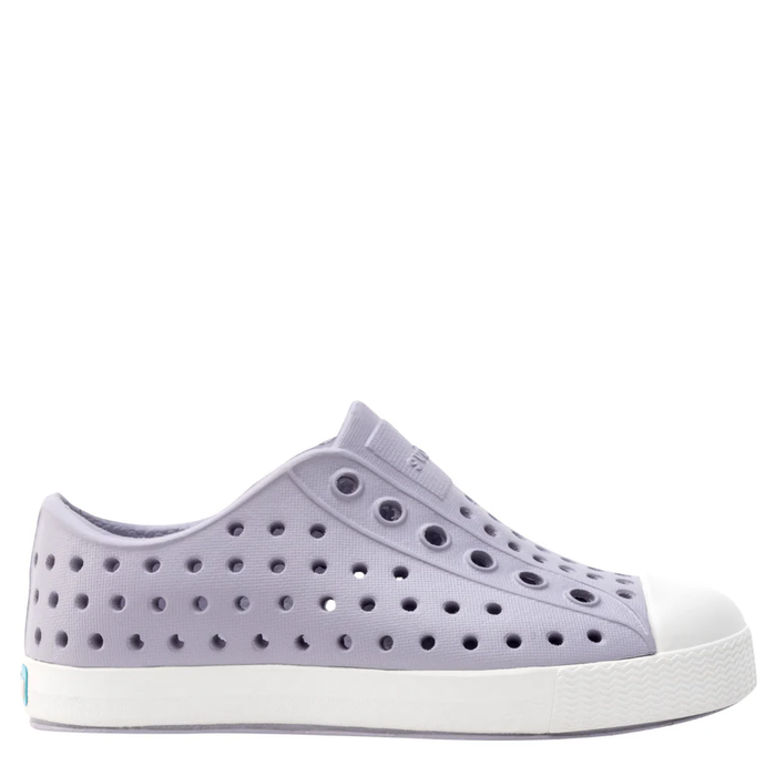 A pair of gray Native Jefferson shoes for kids with a pattern of holes on the upper part and a white sole.