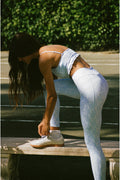 Woman in blue athletic wear stretching outdoors on a bench.