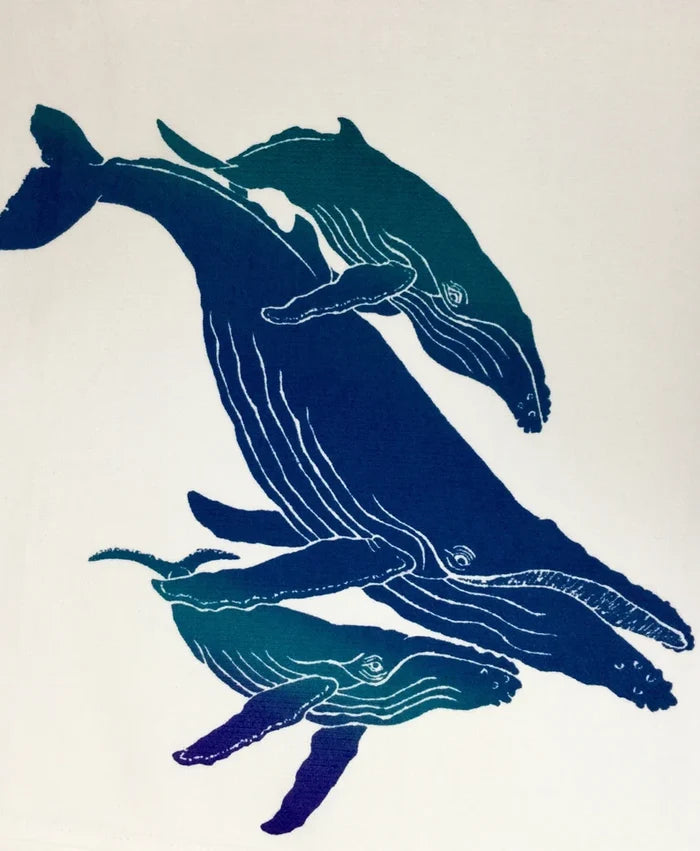 A handscreened kitchen towel featuring a tropical design with humpback whales in blue shades on a white background.