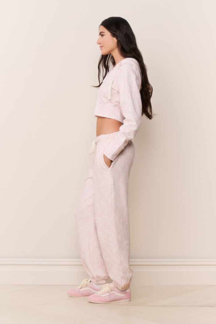Woman wearing a light pink outfit standing against a white wall