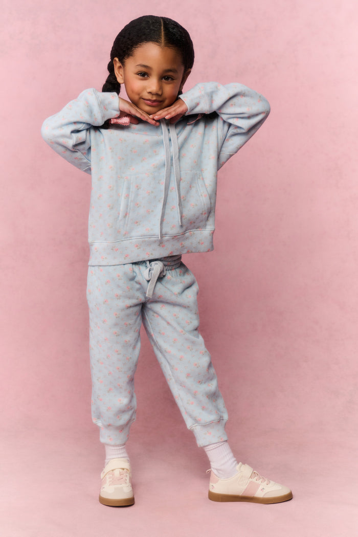 Child wearing a light blue tracksuit on a pink background