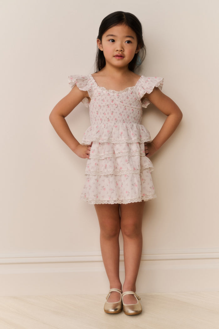 Young girl wearing a floral ruffle dress against a plain background