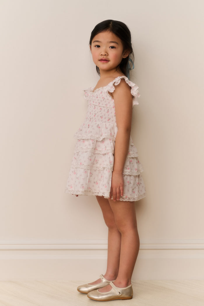 Young girl wearing a floral dress against a plain background
