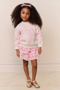 Young girl wearing a pink tie-dye outfit with a white background