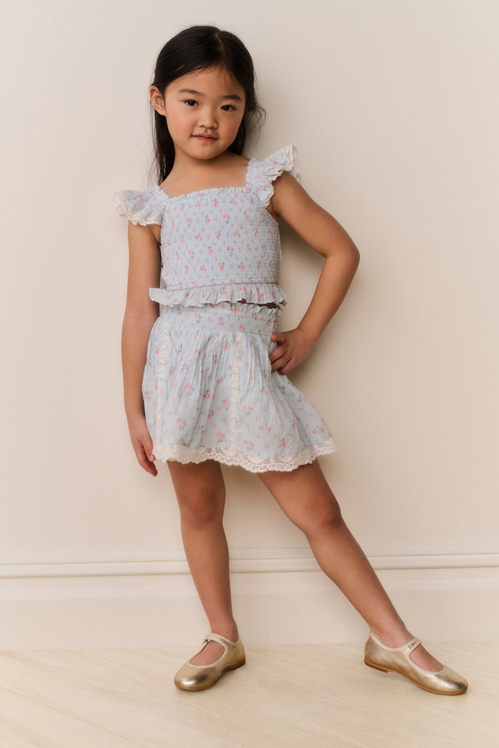 Young girl wearing a Light blue floral lace skirt and top against a plain background