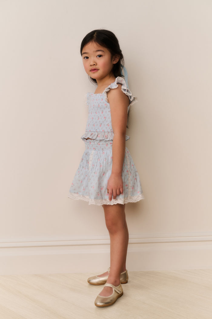 Young girl wearing a Light blue floral lace skirt and top against a plain background