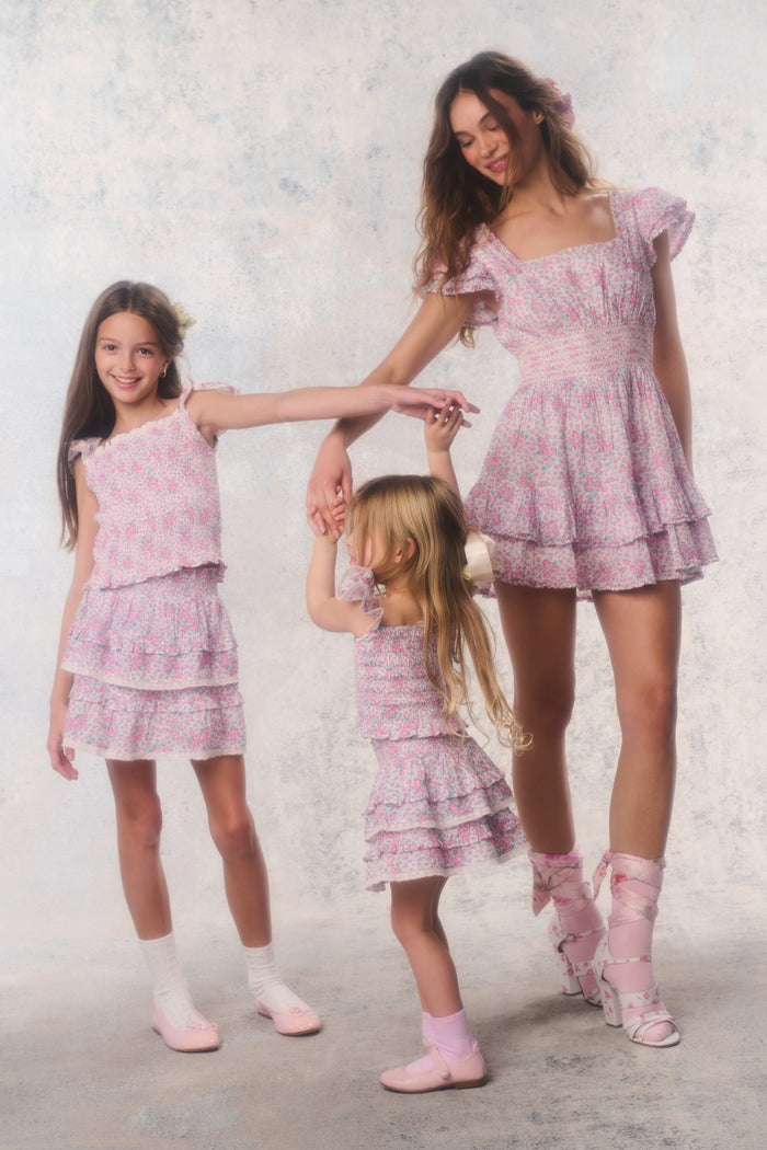 Three women in matching pink outfits standing together against a light background