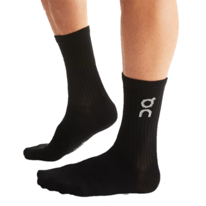 A pair of  adult crew length black socks with a white On Running logo on a white background