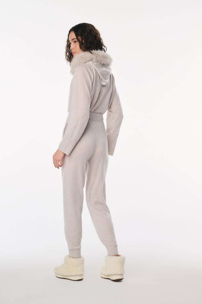 Person wearing a gray jumpsuit with a hood on a white background