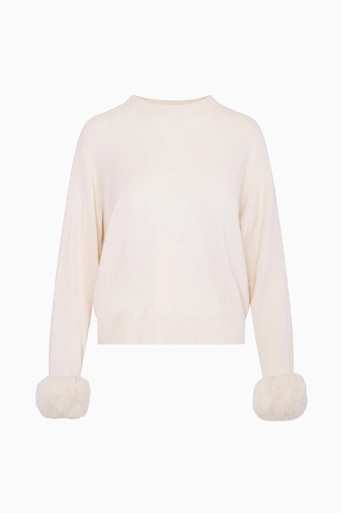 White sweater with pom-pom details on a white background