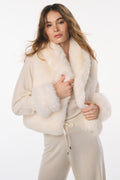 Woman wearing a cream-colored outfit with a fur-lined jacket on a white background