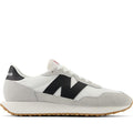 A pair of New Balance sneakers with a white mesh upper, black leather accents, and a herringbone outsole.