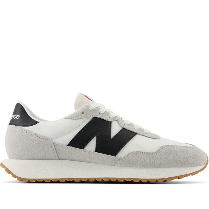 A pair of New Balance sneakers with a white mesh upper, black leather accents, and a herringbone outsole.